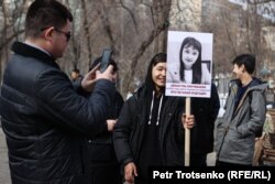 "Әйелдердің лайықты өмірі үшін" митингісіне келгендер тұрмыстық зорлықтан өлген әйелдің суретін ұстап тұр.