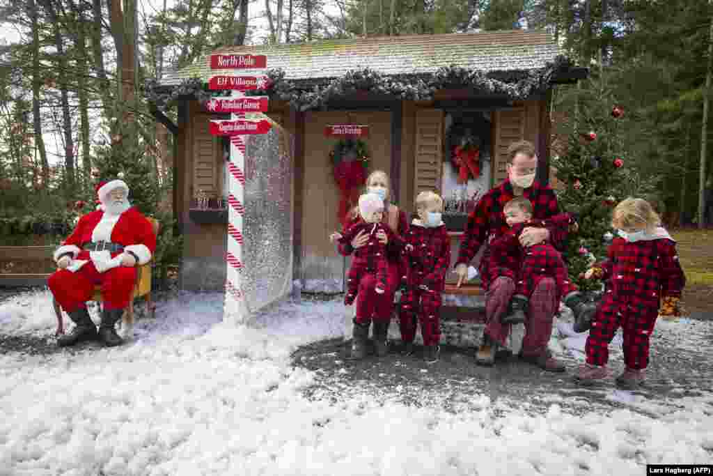 Родина в різдвяних костюмах позує для фотографії з Санта-Клаусом через оргскло між ними, щоб уберегтися від можливої небезпеки заразитися коронавірусною хворобою. Кінгстон, Онтаріо, Канада, 28 листопада 2020 року